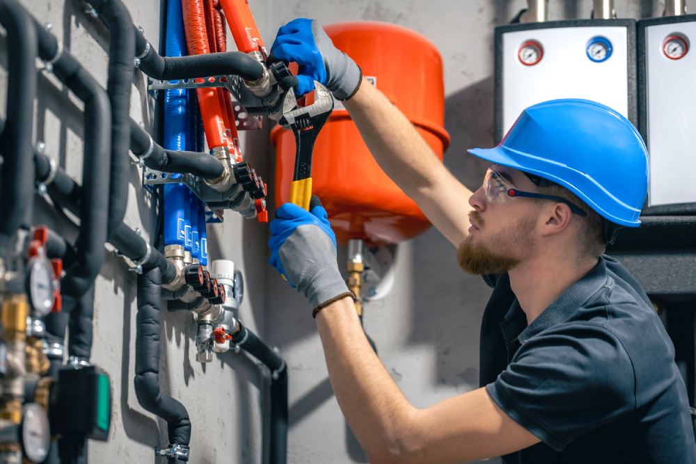 A man installs a heating system in a house and checks the pipes with a wrench. A man installs a heating system in a house and checks the pipes with a wrench.